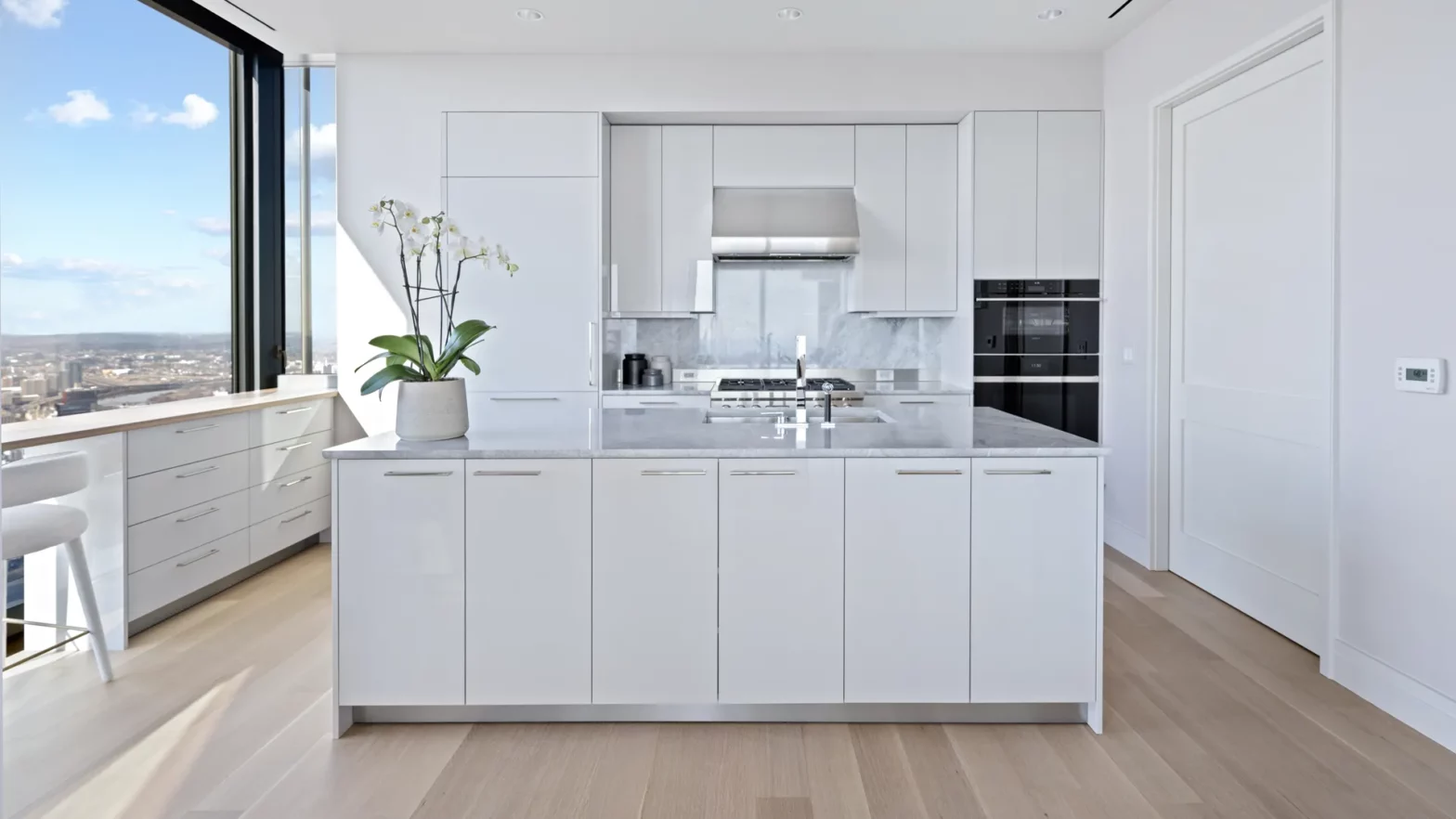 Four Seasons One Dalton Signature Residence kitchen with island and floor-to-ceiling windows overlooking Back Bay, Boston.